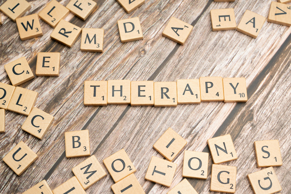 Scrabble tiles spelling THERAPY on a wooden surface